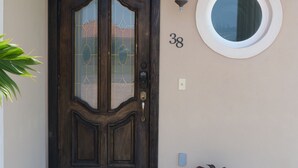 A dark wooden double door with glass panels, a round window, and the number 38 on the wall. - Taste of Paradise (Nassau)