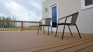 A wooden deck with two chairs and a door. - Taste of Paradise (Nassau)