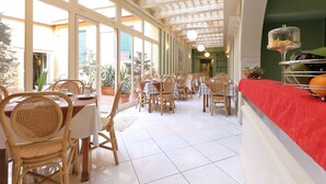 Un restaurante con comedor interior, sillas y mesas de madera, y una barra roja.