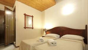 Habitación de hotel con dos camas, una puerta de madera, un espejo y una lámpara.