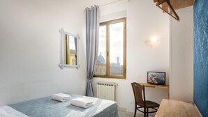Una habitación pequeña y ordenada con cama, escritorio y silla.