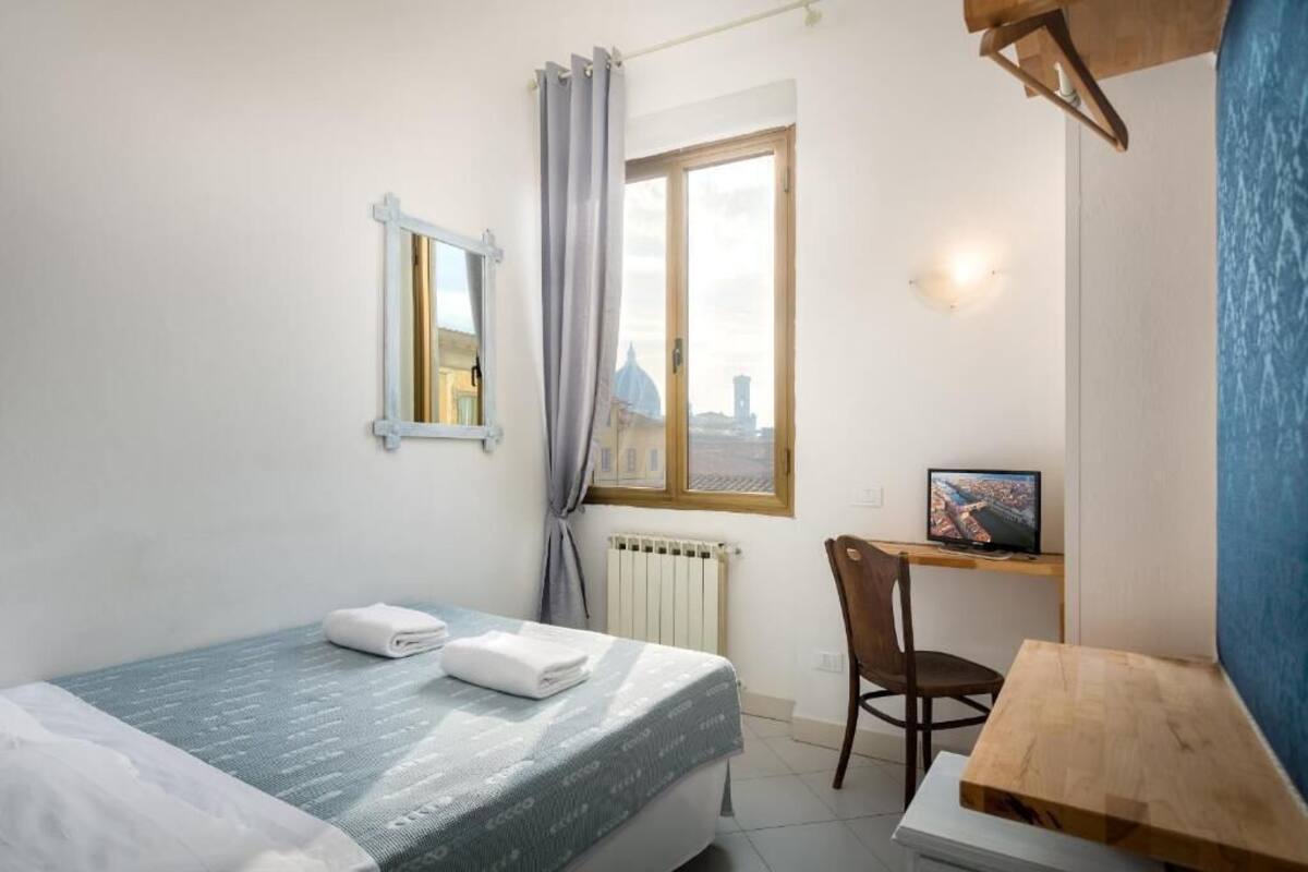 A small, tidy room with a bed, a desk, and a chair.