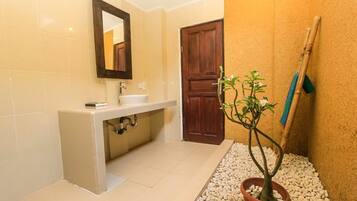 A bathroom with a sink, mirror, and a potted plant.