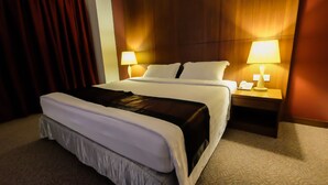 A hotel room with a large bed, two bedside tables with lamps, and a wooden headboard. - Times Hotel (Bandar Seri Begawan)