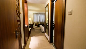 A hotel hallway with a bed, chairs, a desk, and a lamp. - Times Hotel (Bandar Seri Begawan)