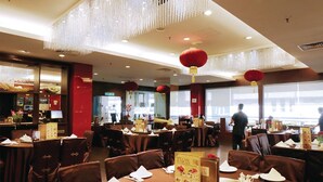 A restaurant with multiple tables, brown chairs, and hanging red lanterns. - Times Hotel (Bandar Seri Begawan)
