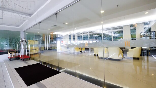 A modern lobby with glass partitions, a reception desk, and seating areas. - Times Hotel (Bandar Seri Begawan)