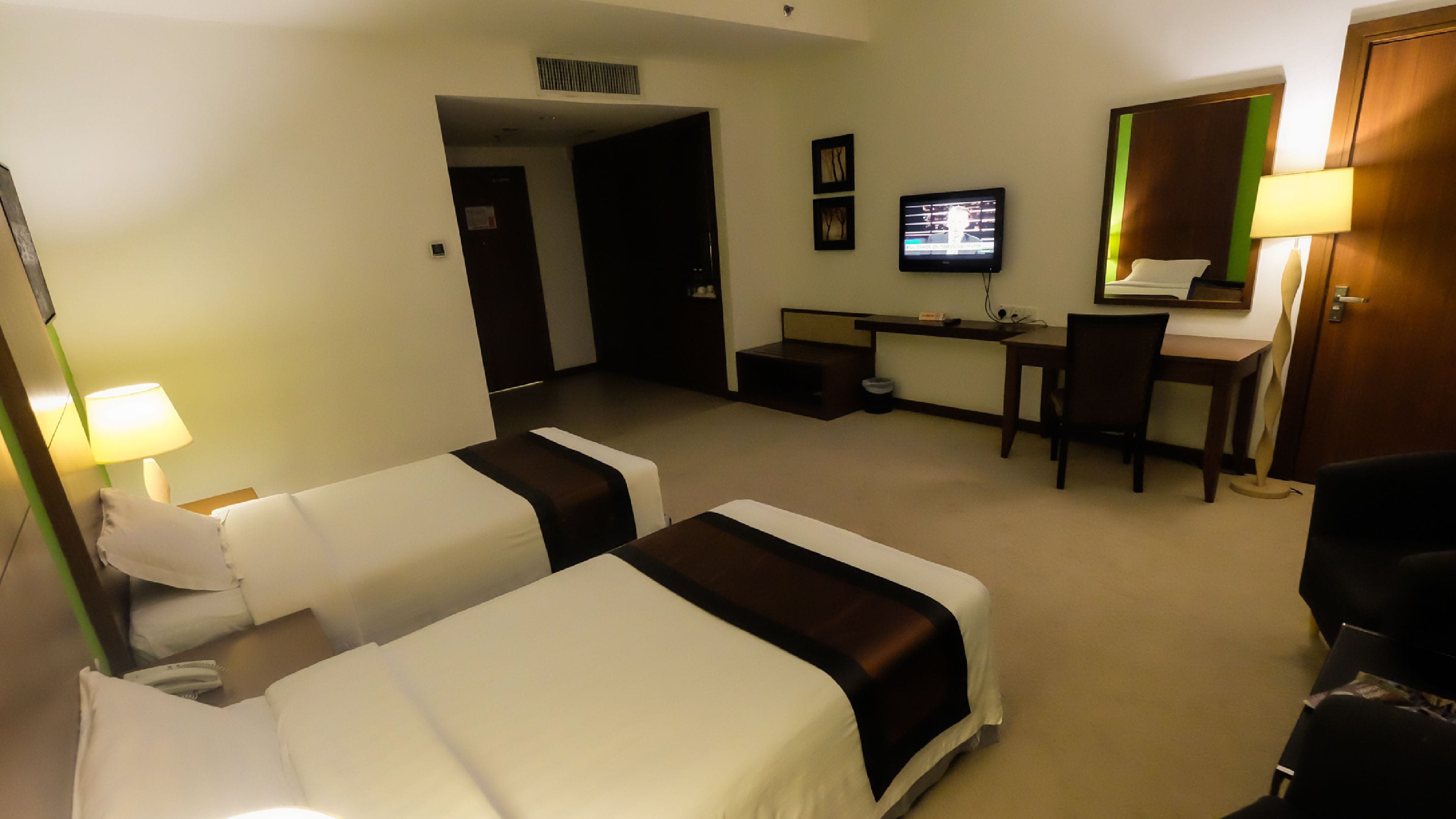 Une chambre d’hôtel avec deux lits, un bureau, une chaise, une télévision et une lampe.