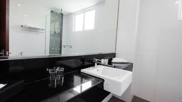 A modern bathroom with a black countertop, white sink, and a glass shower enclosure.