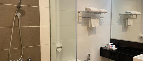 Un baño moderno con cabina de ducha de vidrio, inodoro, lavabo y espejo.