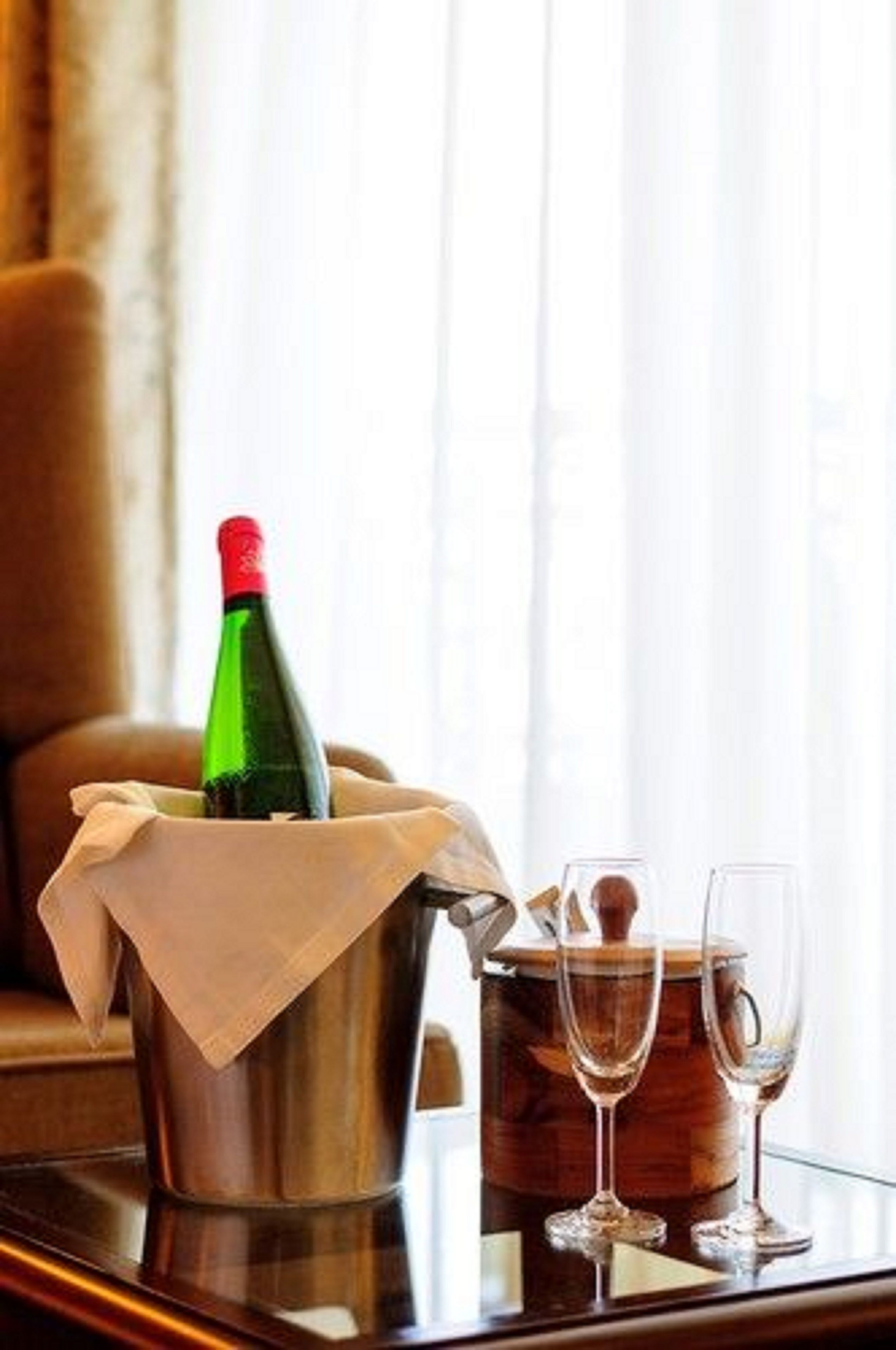 A champagne bottle in a bucket on a table with two glasses beside it.