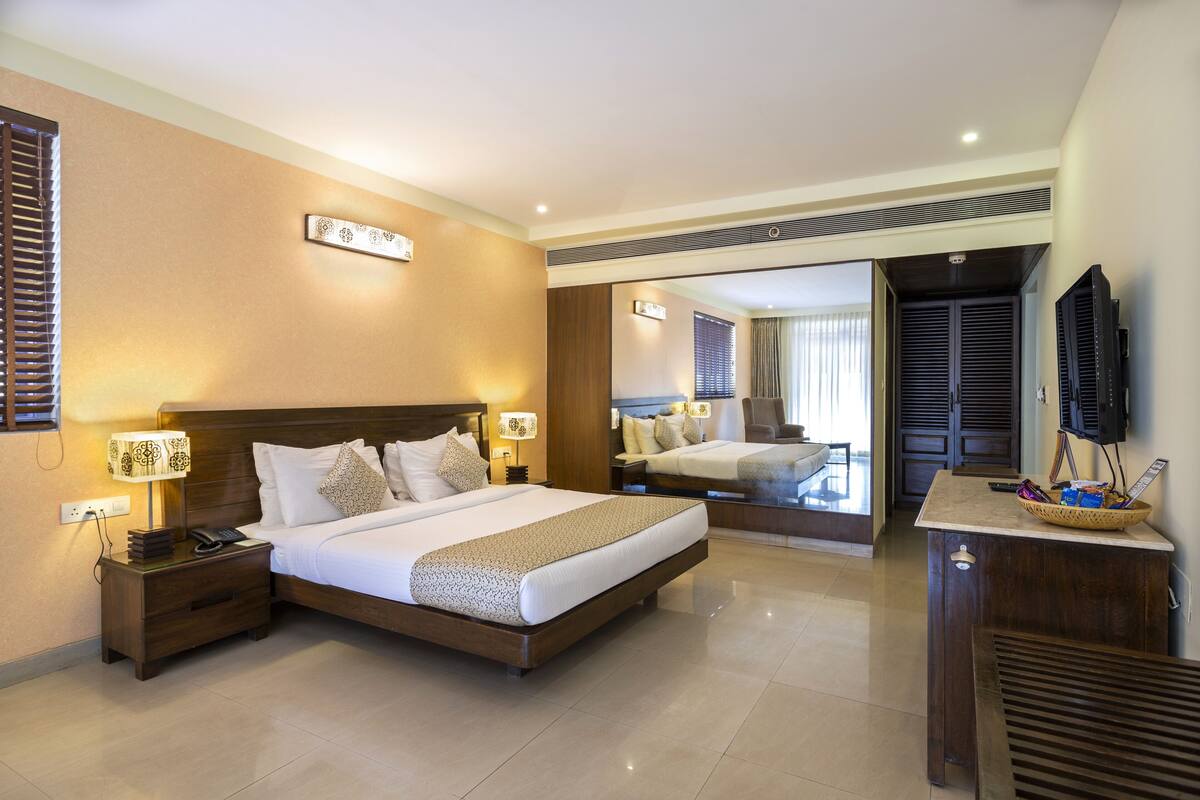 Une chambre d’hôtel avec un grand lit, des tables de chevet avec des lampes, une télévision et un miroir.