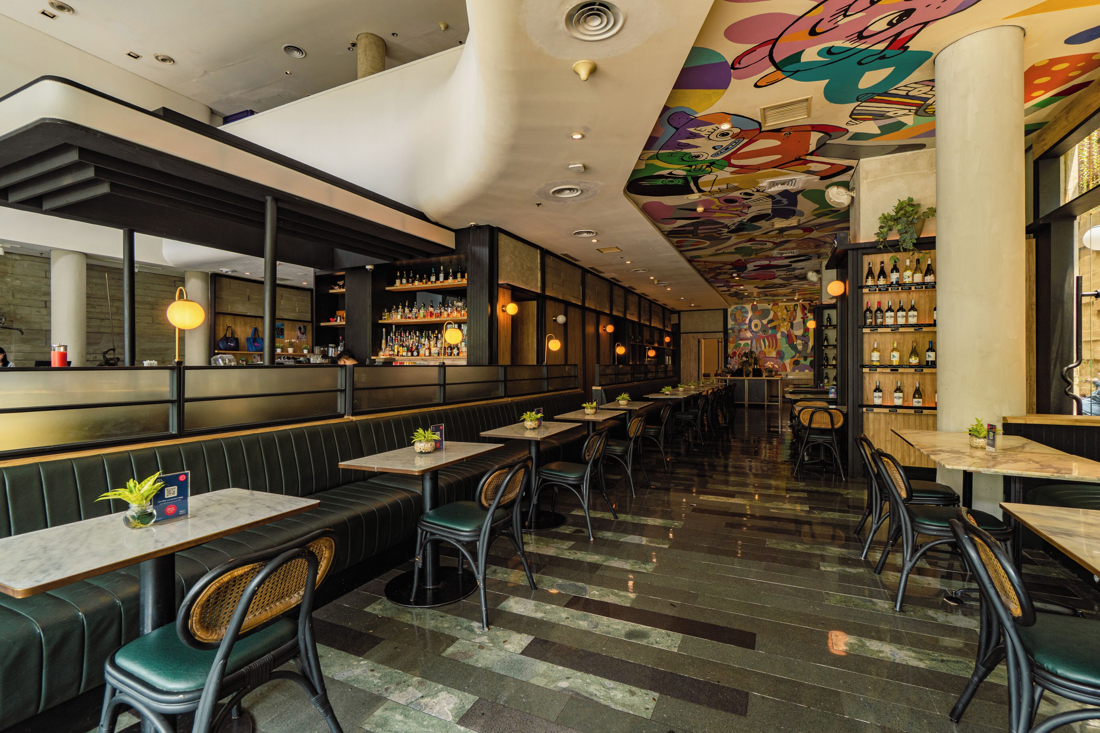 Un restaurante con cabinas, mesas y una zona de bar.