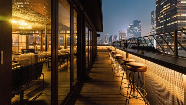 A rooftop bar with a city view, wooden flooring, and bar stools. - ARTOTEL Thamrin Jakarta (Jakarta)