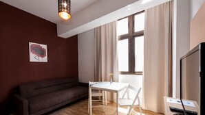 A modern living room with a brown sofa, a white table, and a TV. - Hotel Las Palmas Urban Center (Las Palmas de Gran Canaria)