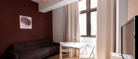 Una sala de estar moderna con un sofá marrón, una mesa blanca y un televisor.