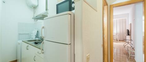 A compact kitchen with a refrigerator, microwave, and a small sink.