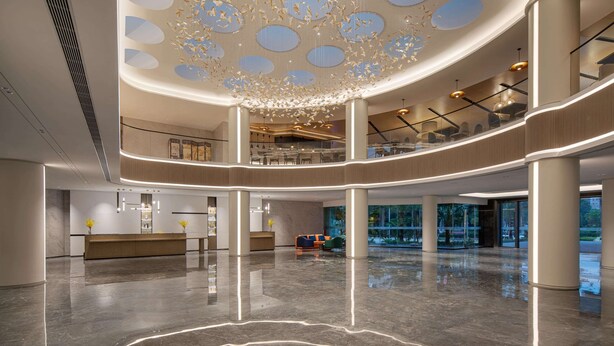 Un vestíbulo amplio con techo alto, una recepción, zona de estar y vistas al exterior.