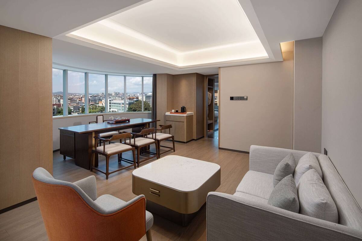 Een moderne hotelkamer met een eethoek, kitchenette en een bank met kussens.