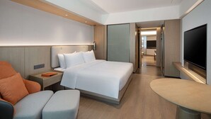 Una habitación de hotel moderna con una cama grande, un televisor, un escritorio y una zona de estar.