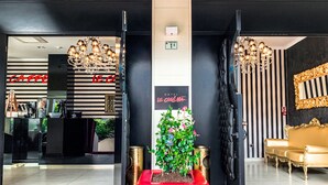 A hotel lobby with a red carpet, a reception desk, a chandelier, a potted plant, and a gold sofa. - Hotel Le Cinèma (Gatteo)