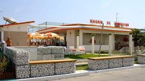 A restaurant with outdoor seating, a sign reading "BAGNO IL GABBIANO", and a modern architectural design. - Hotel Le Cinèma (Gatteo)