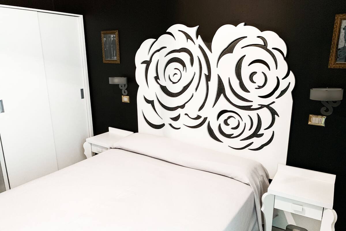 Ein Schlafzimmer mit Bett, Nachttisch, Kleiderschrank und einer dekorativen Wandverkleidung.
