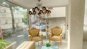 A modern room with two ornate chairs, a tufted sofa, and a glass coffee table. - Hotel Le Cinèma (Gatteo)