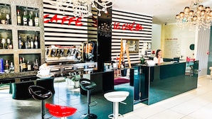 A bar area with a counter, stools, and a variety of bottles on shelves. - Hotel Le Cinèma (Gatteo)