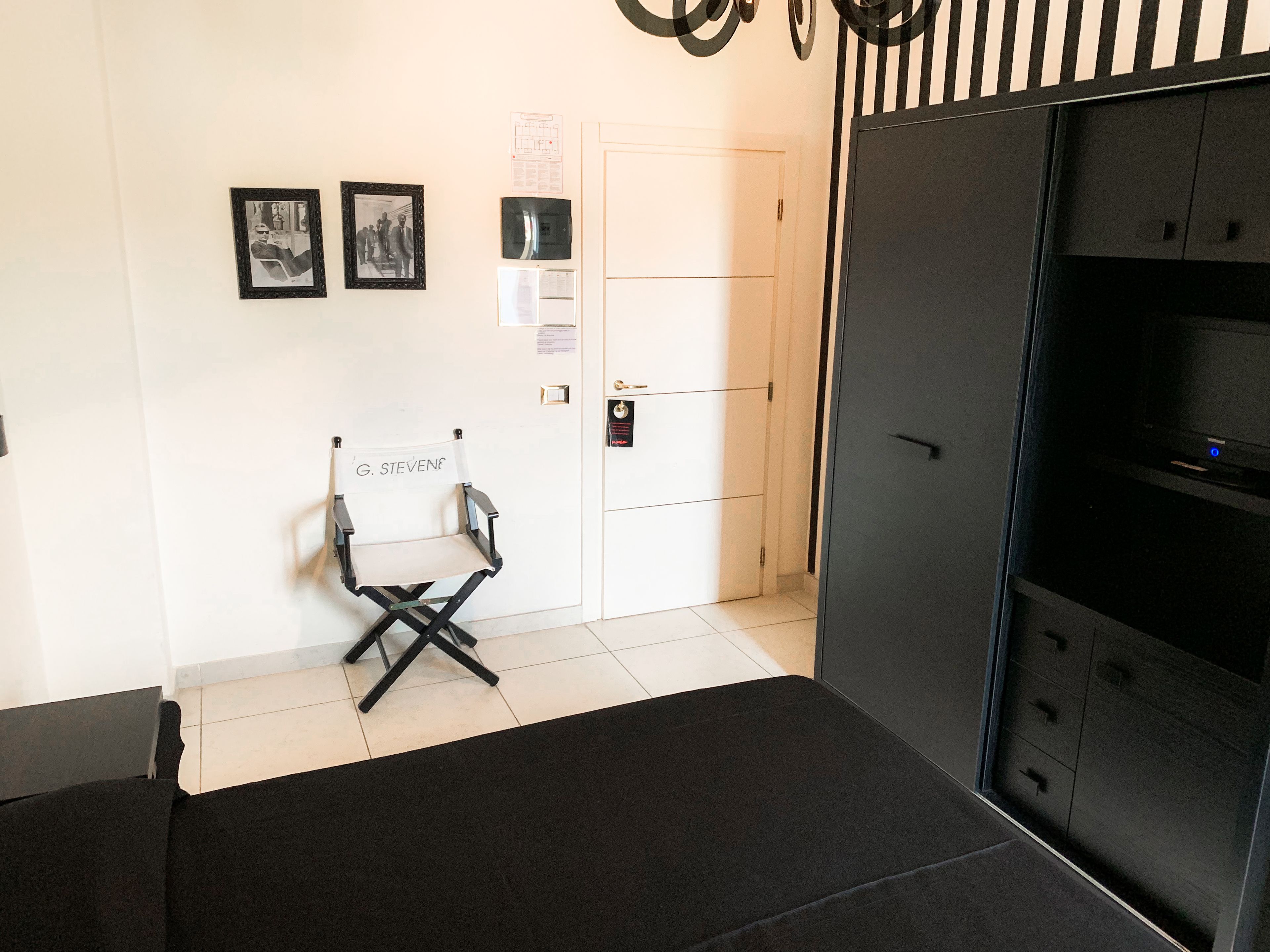 A room with a black sofa, a black chair, a black cabinet, and two framed pictures on the wall.