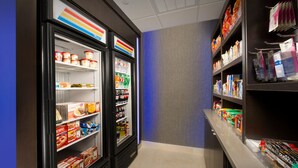 A hotel corridor with refrigerated display cases filled with food items and shelves stocked with toiletries and personal care products. - Holiday Inn Express & Suites Waco South by IHG (Waco)