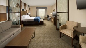 A hotel room with a bed, sofa, armchair, desk, and TV. - Holiday Inn Express & Suites Waco South by IHG (Waco)