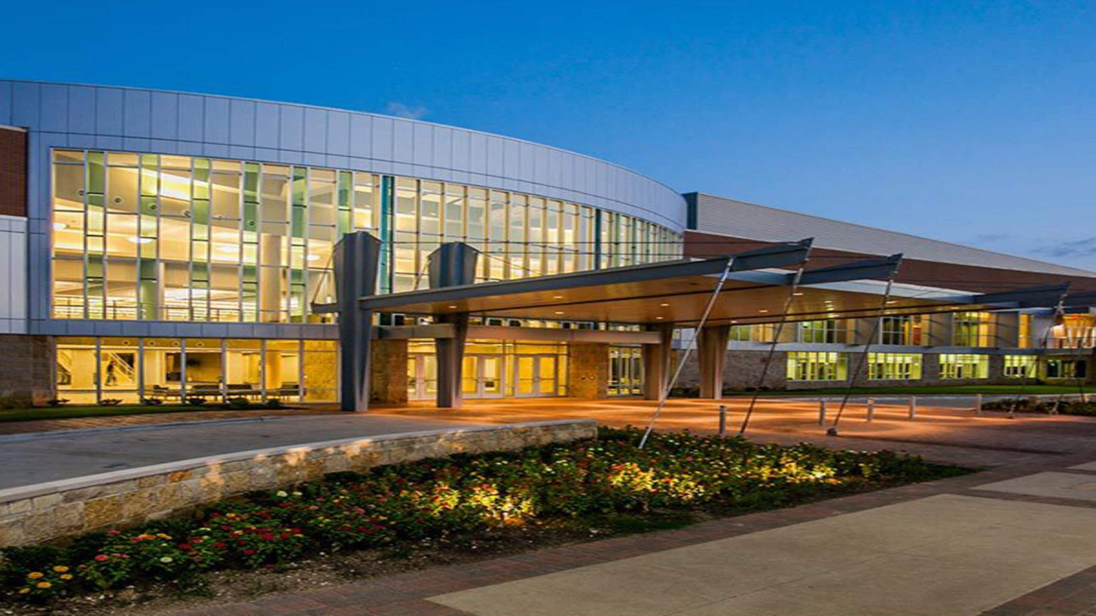 A modern building with a curved facade, large windows, and a covered entrance area.
