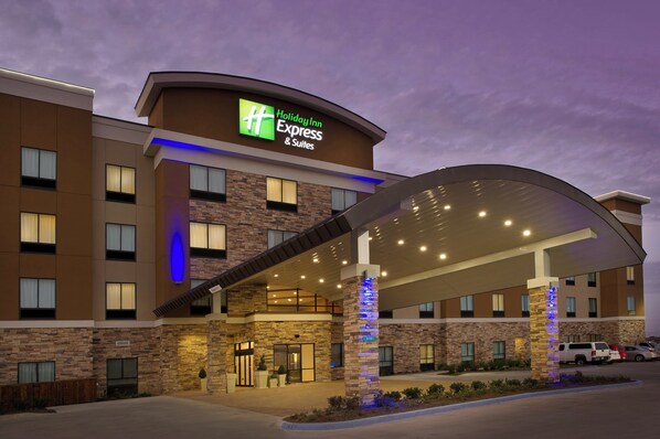 A Holiday Inn Express & Suites building with a covered entrance, stone facade, and illuminated signage. - Holiday Inn Express & Suites Waco South by IHG (Waco)