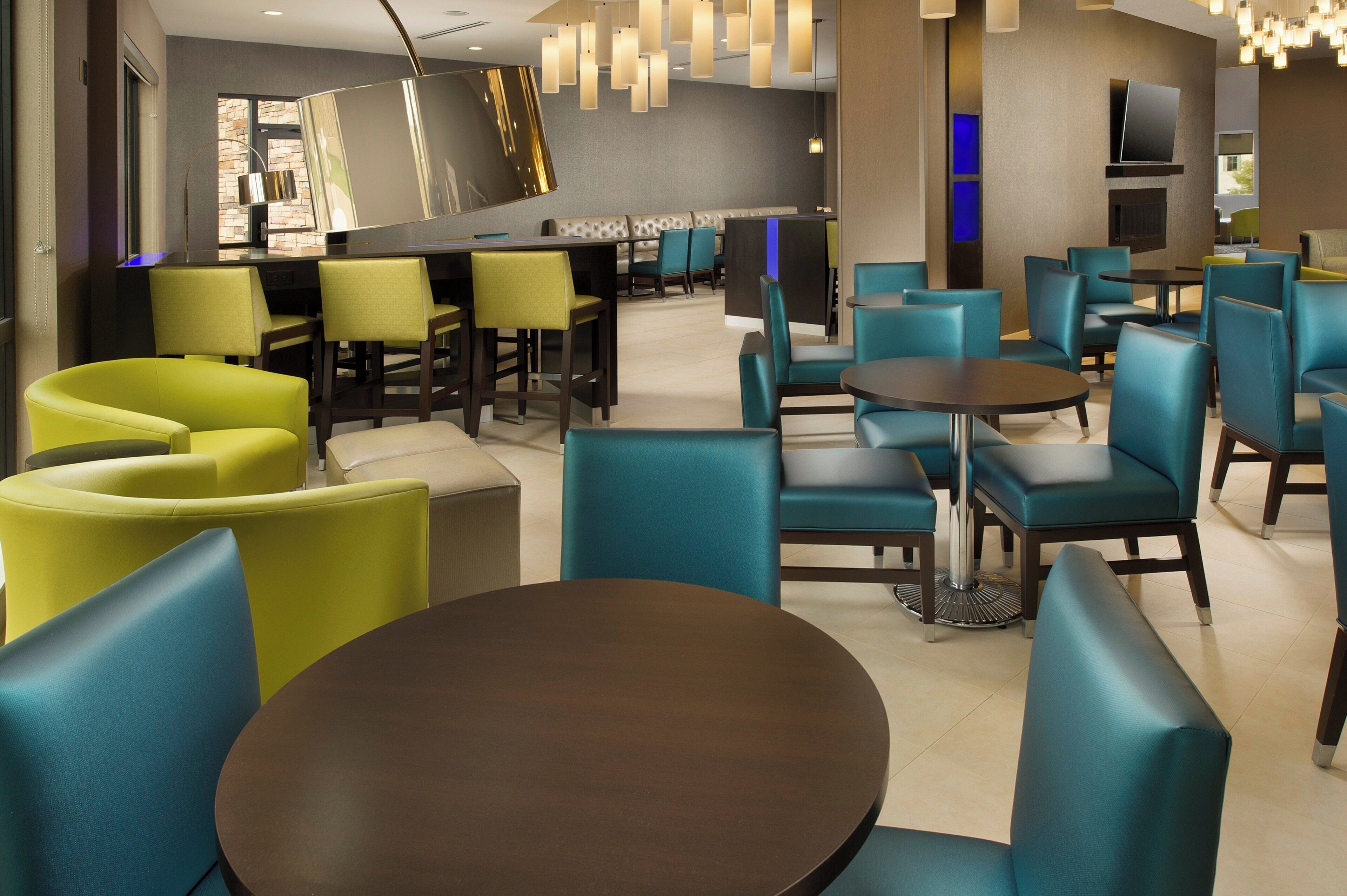 A modern hotel lobby with a bar area, seating arrangements, and a television.