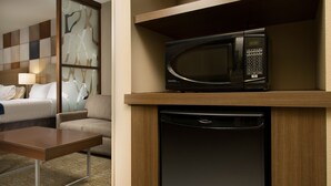 A hotel room with a bed, a sofa, a coffee table, a microwave, and a dishwasher. - Holiday Inn Express & Suites Waco South by IHG (Waco)