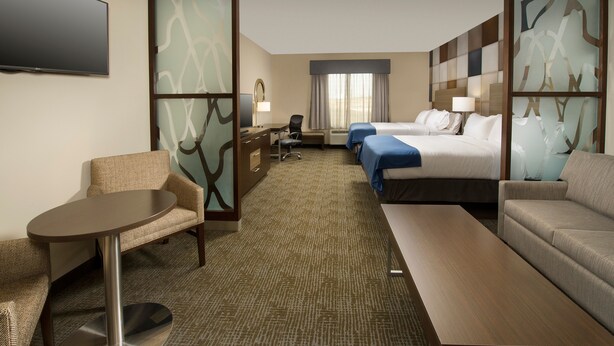 A hotel room with a bed, two bedside tables, a desk with a chair, a sofa, a small round table, and a TV. - Holiday Inn Express & Suites Waco South by IHG (Waco)