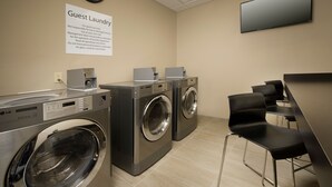 A guest laundry area with two washing machines, a clock, and a flat-screen TV.