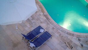 Een buitenzwembad, parasols voor strand/zwembad