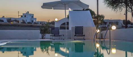 Een buitenzwembad, parasols bij het zwembad en ligstoelen