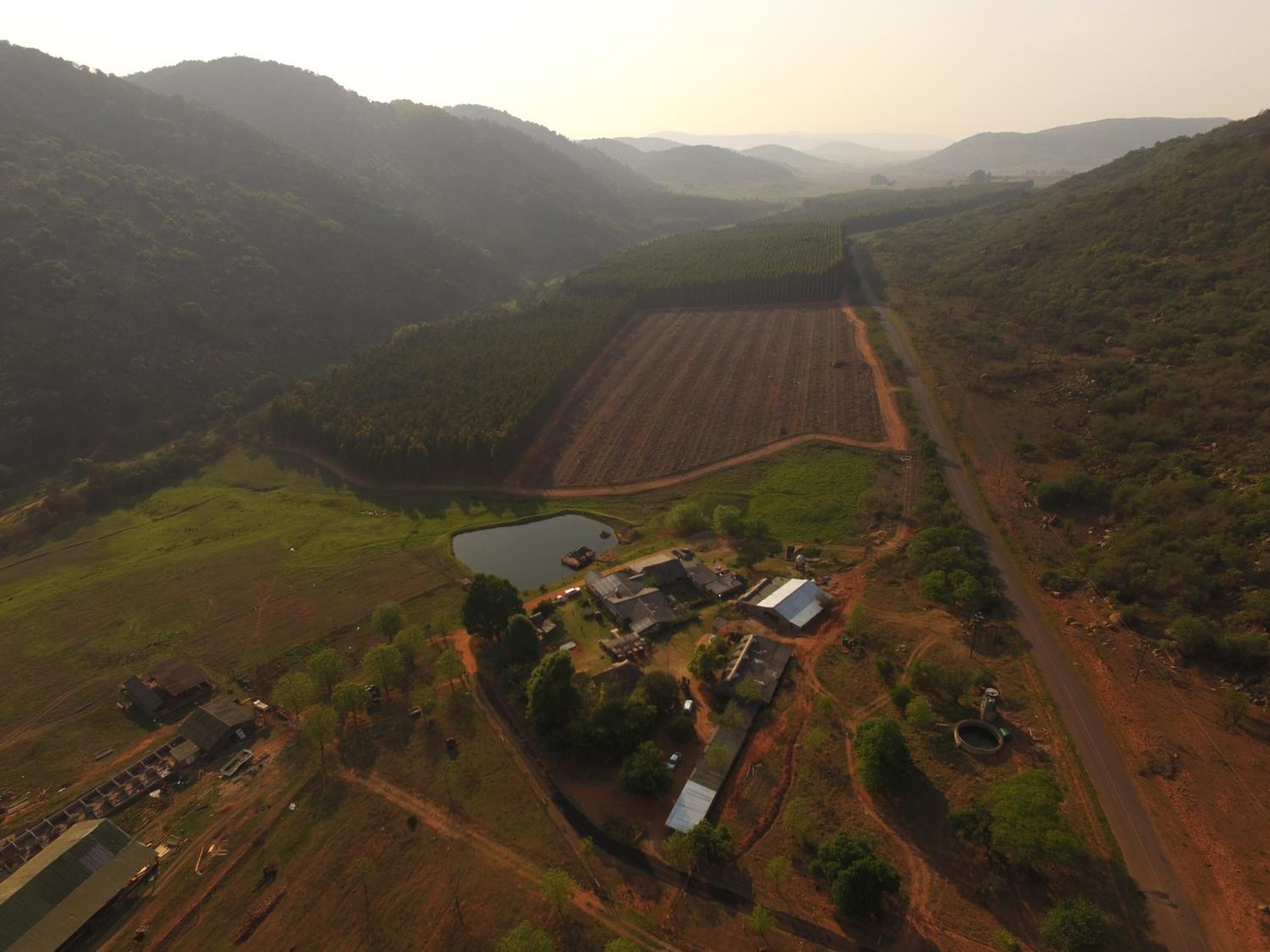 An aerial view of a rural landscape with fields, a small pond, and scattered buildings.