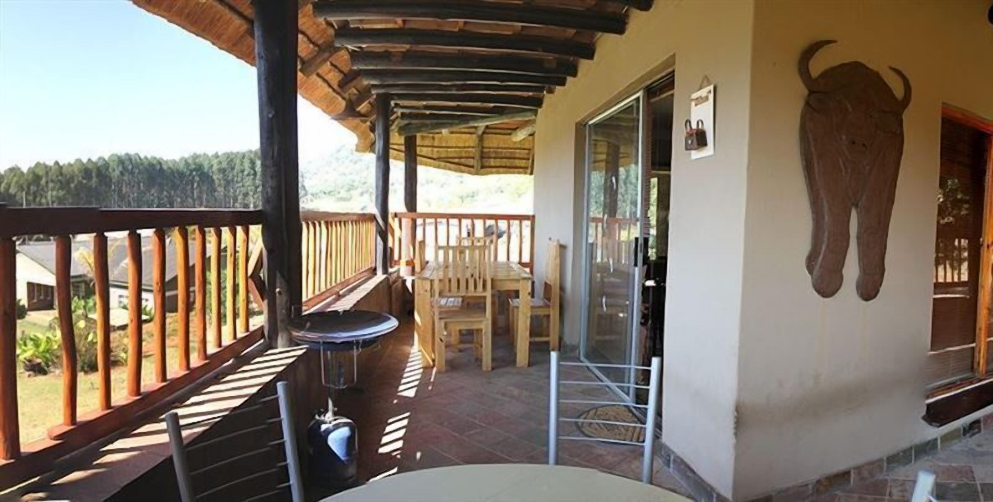 A balcony with a wooden railing, a table, and chairs.