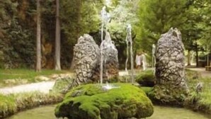 A naturalistic garden with a small pond, moss-covered rocks, and a wooden path. - Balneario Serón (Jaraba)