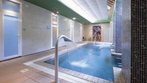 A swimming pool with a water fountain, tiled walls, and a green ceiling. - Balneario Serón (Jaraba)
