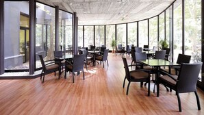 A spacious indoor area with large windows, wooden flooring, and modern furniture. - Balneario Serón (Jaraba)