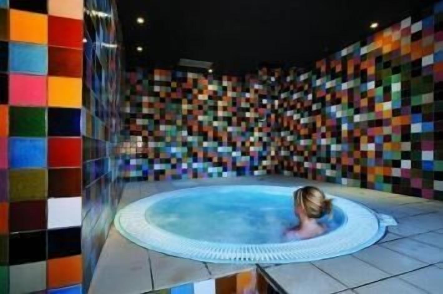 Un jacuzzi en una habitación con paredes de mosaicos coloridos.
