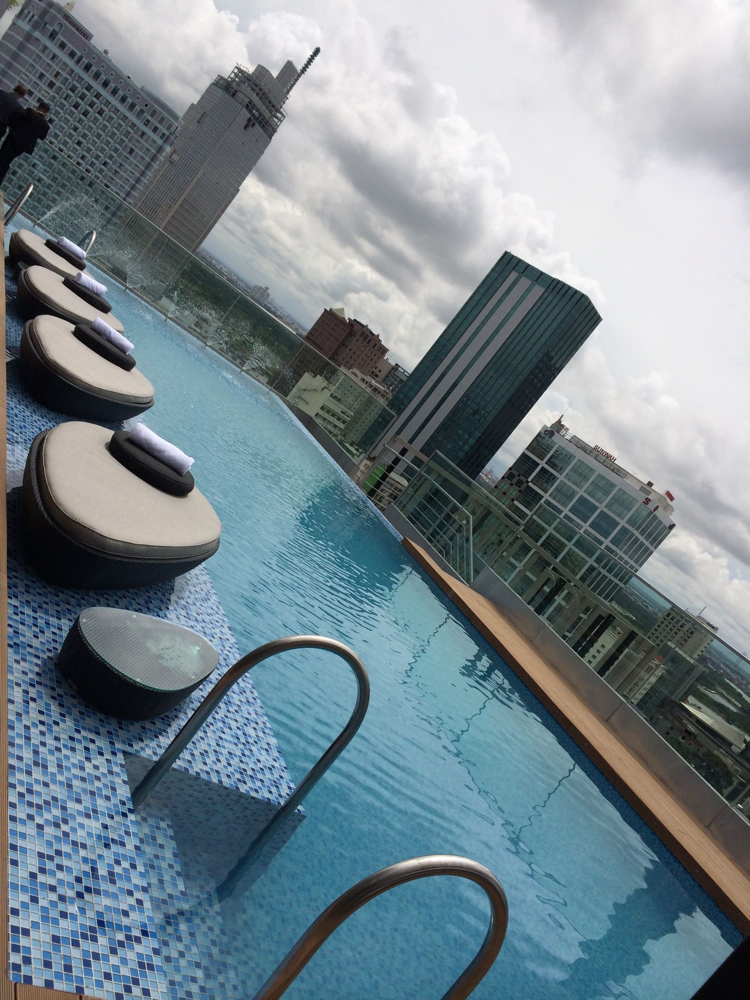 Piscina en la azotea con sillas de descanso y vista panorámica de la ciudad.