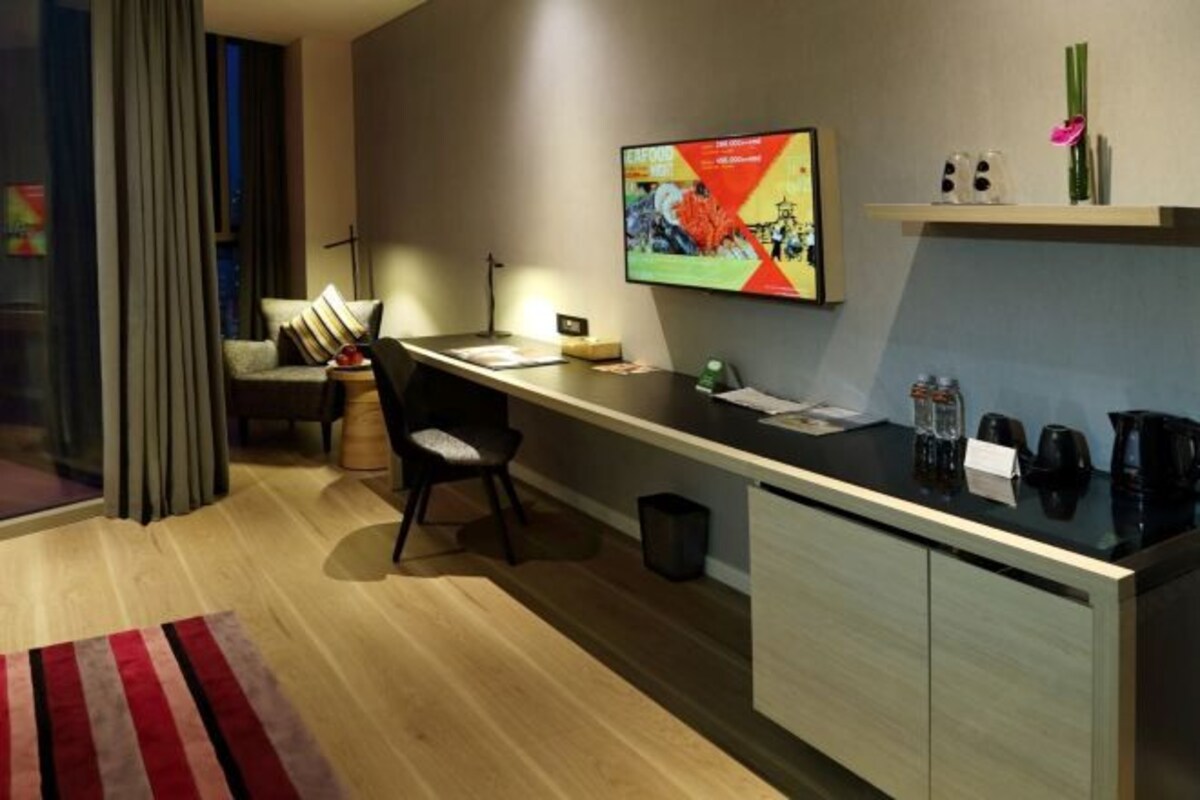 Een moderne hotelkamer met een bureau, stoel en een aan de muur bevestigde televisie.