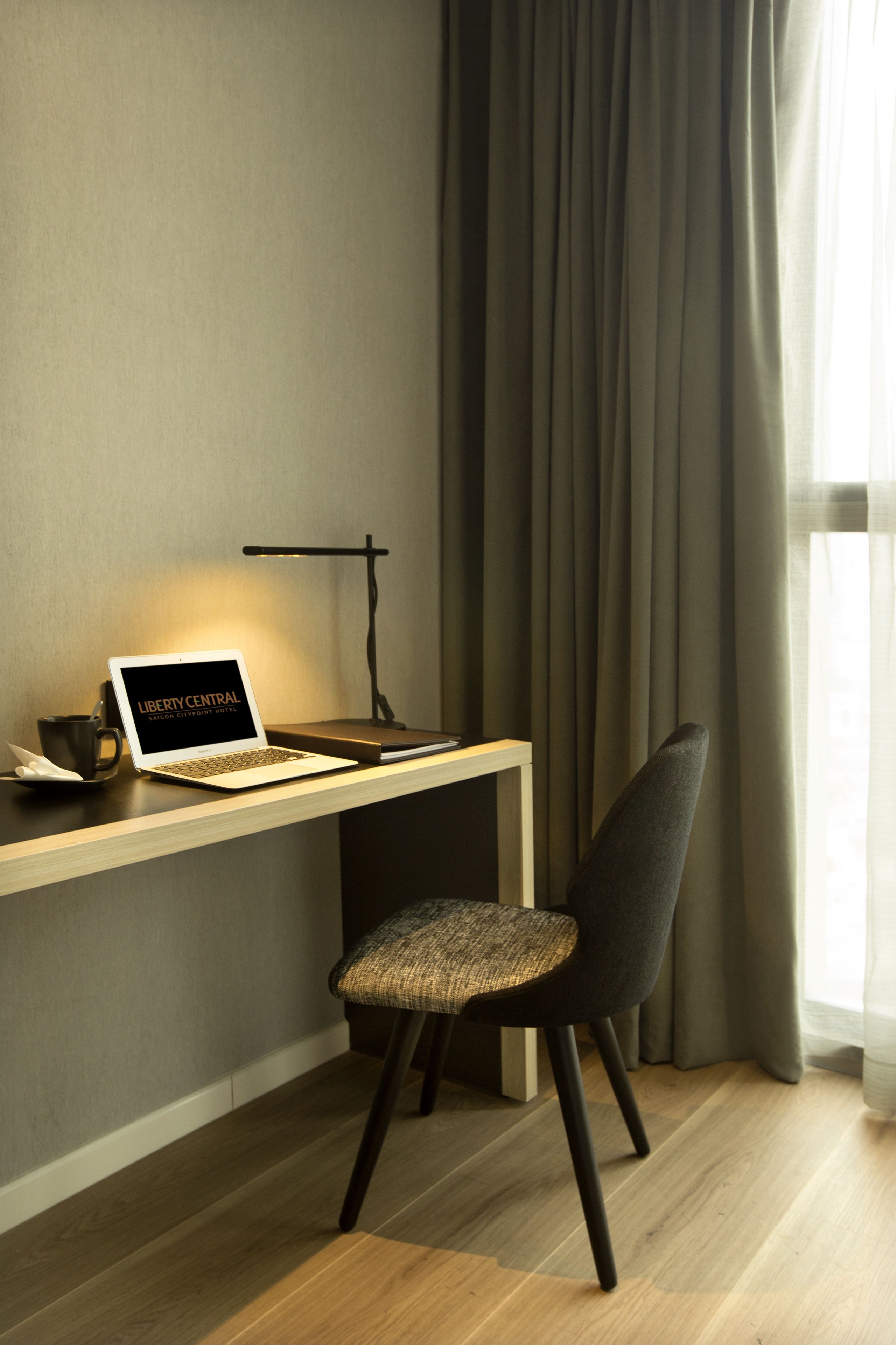A modern workspace with a laptop, desk lamp, and chair.