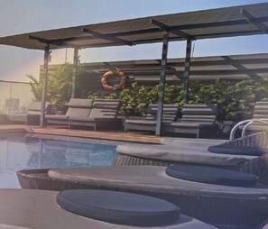 Relax by the pool, surrounded by lounge chairs and a shaded pergola.